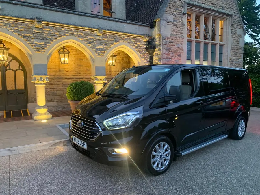 The eight seater waiting outside a lit Sherborne stone building at dusk